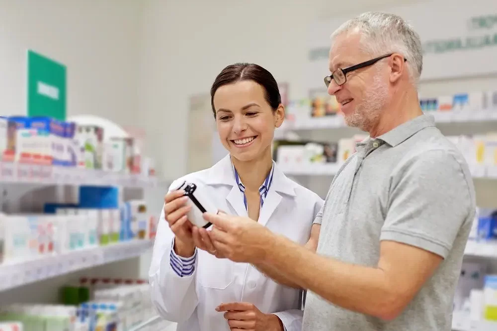 Pharmacist showing drug to senior man at lien pharmacy